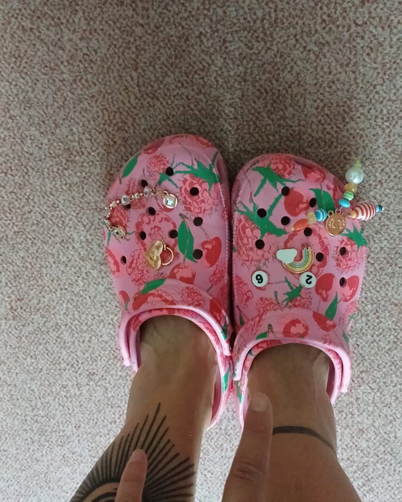 Persönliches Detail: pinke Crocs mit Pins.